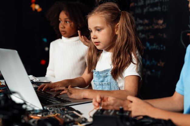 Schlaues Mädchen mit weißem Schnürsenkel lernt Robotik-Technologie mit einem Laptop Erudition