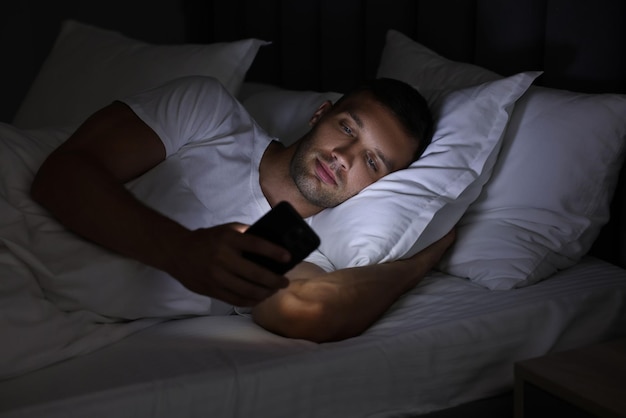 Schlechte Angewohnheit Mann benutzt Smartphone nachts im Bett