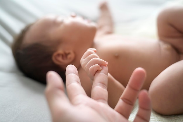 Foto schließen der hand, die den finger des neugeborenen babys hält