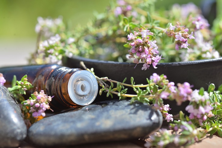 Foto schließen sie auf flasche des ätherischen öls, das auf stein mit aromatischem kraut verschüttet wird