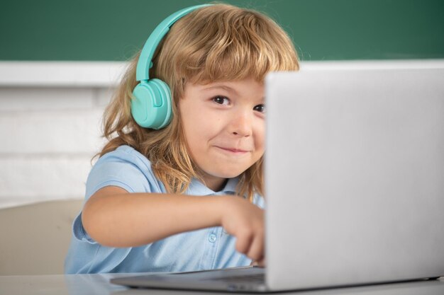 Schließen Sie das Porträt eines süßen Jungen in Kopfhörern mit einem Laptop und lernen Sie online mit Videoanruf te