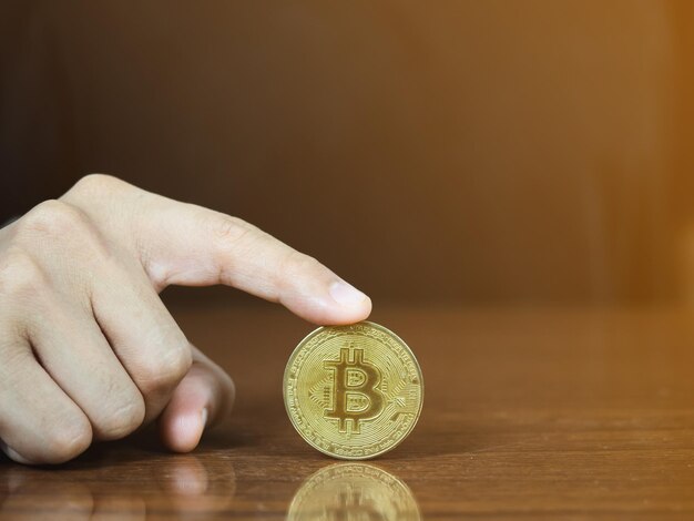 Schließen Sie den Finger, der Bitcoin auf dem Tisch berührt