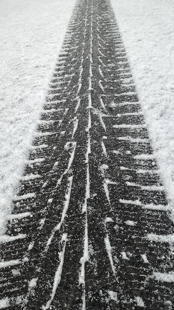 Foto schließen sie den schwarzen winterreifen-laufflächenabdruck auf weißem schnee der straßenoberfläche