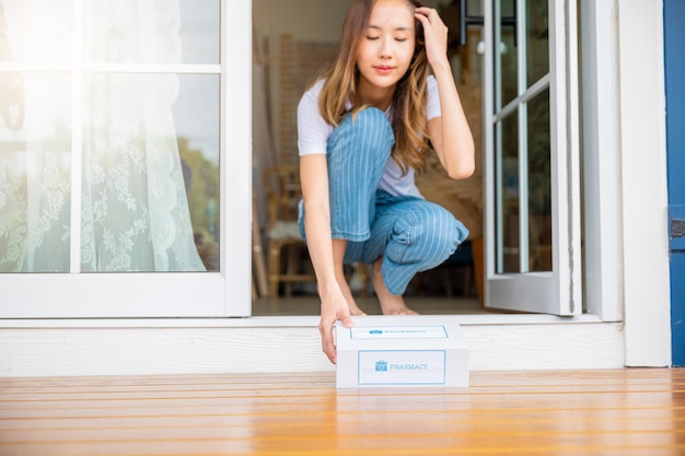 Schließen Sie die Hände einer kranken asiatischen Frau, die an der Tür sitzt, um eine Erste-Hilfe-Apothekenbox für Medikamente vom Krankenhauslieferdienst im Erdgeschoss zu erhalten, weibliche Patienten kaufen Drogerie-Online-Geschäft, Gesundheitswesen