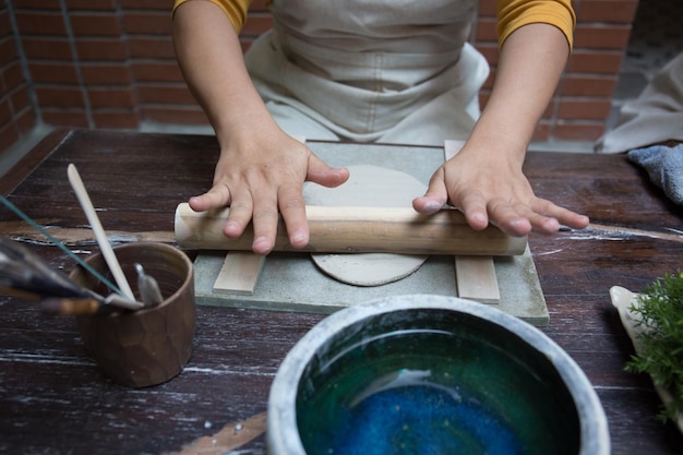 Foto schließen sie die hand der asiatischen frau mit der töpferscheibe, um eine teekanne in der werkstatt herzustellen