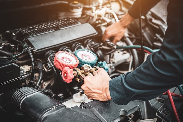 Schließen Sie die Hand des Mechanikers mit der Füllstandsanzeige für Autoklimaanlagen.