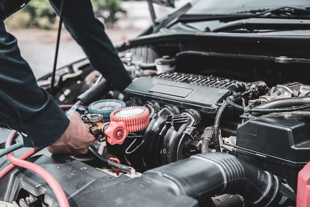 Schließen Sie die Hand des Mechanikers mit der Füllstandsanzeige für Autoklimaanlagen.