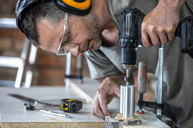 Schließen Sie einen Tischler, der im Haus mit Holz und Bauwerkzeugen arbeitet