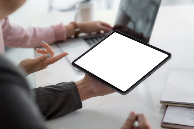 Schließen Sie Geschäftsleute, die einen leeren weißen Bildschirm des Tablets im Konferenzraum halten.