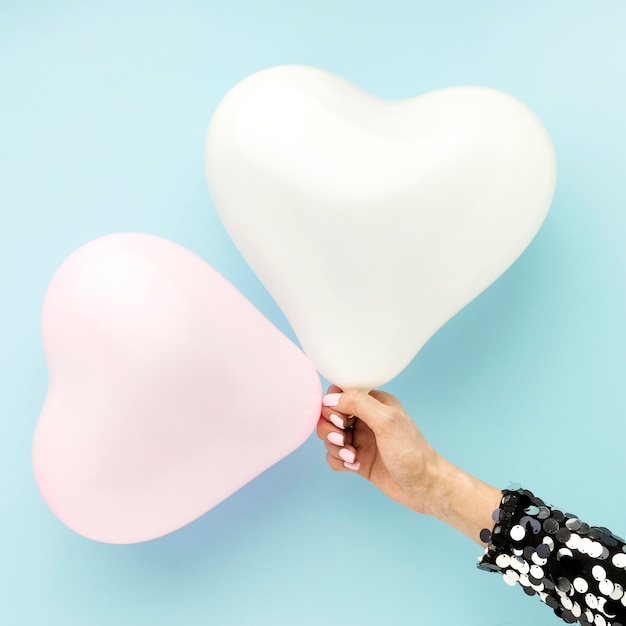 Foto schließen sie hände mit herzförmigen luftballons