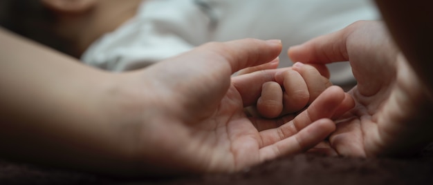 Schließen Sie herauf Ansicht der Mutterhände, die winziges Hand-Neugeborenes halten