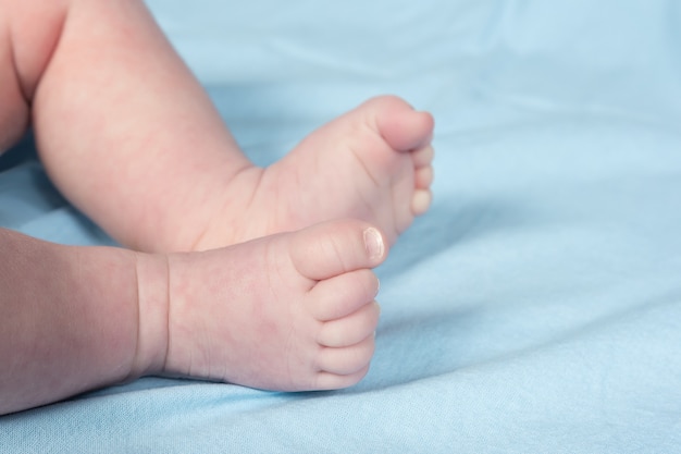 Schließen Sie herauf Ansicht der neugeborenen Babybeine auf einem Bett.