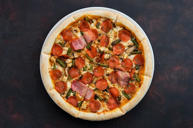Schließen Sie herauf Ansicht der Pizza mit Huhn, Pepperoniwurst, Speck und grüner Bohne