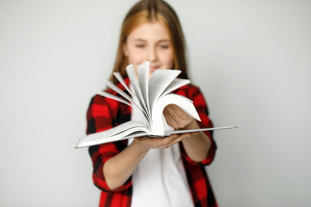 Foto schließen sie herauf ansicht des defokussierten offenen buches, auf unscharfem hintergrundmädchen, das buch hält.