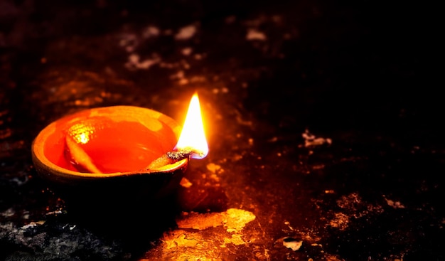 Schließen Sie herauf Bild einer beleuchteten Tondiya oder -lampe auf dem Boden auf Diwali, einem indischen hinduistischen Lichterfest, das auf schwarzem Hintergrund isoliert ist