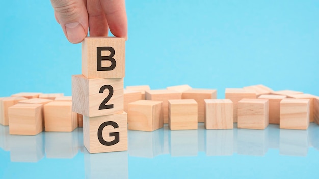 Foto schließen sie herauf bildhand eines mannes, der einen hölzernen würfel mit buchstaben b2g auf blauem hintergrund der hölzernen würfel mit kopienraum hält