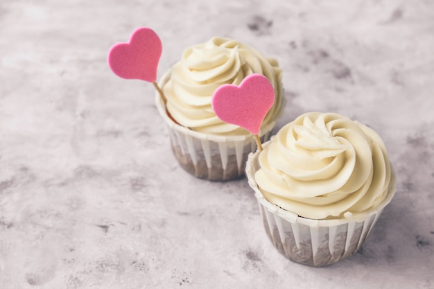 Schließen Sie herauf Cupcakes mit rosa Herzen auf einem grauen Betontischkopierraum