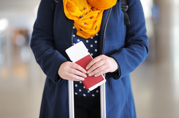 Schließen Sie herauf das Foto der Frau Pass und Bordkarte am Flughafen halten