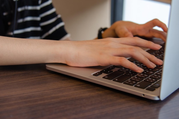 Schließen sie herauf das handmädchen, das tastaturcomputer laptop digitales online-netzwerkkommunikationsinternet auf dem tisch eingibt