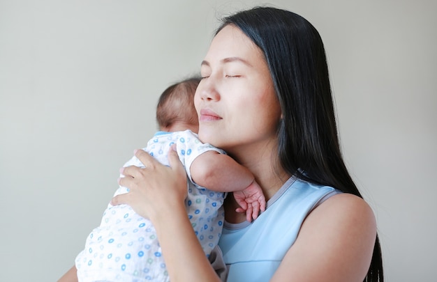 Schließen Sie herauf das tragende Kind der asiatischen Mutter im Schlafzimmer.