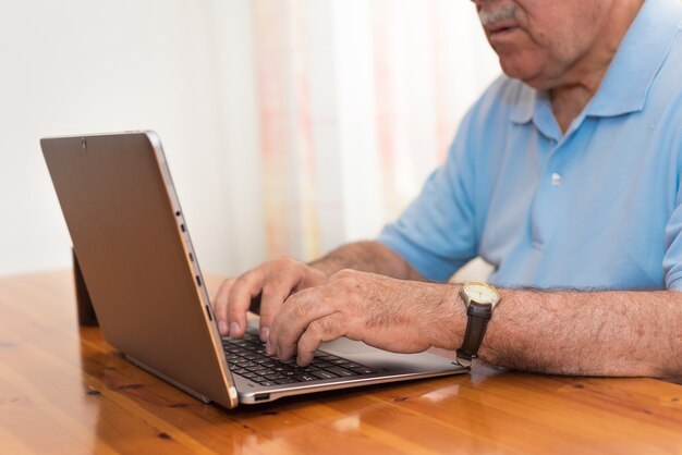 Schließen Sie herauf den älteren Mann, der an Laptop arbeitet