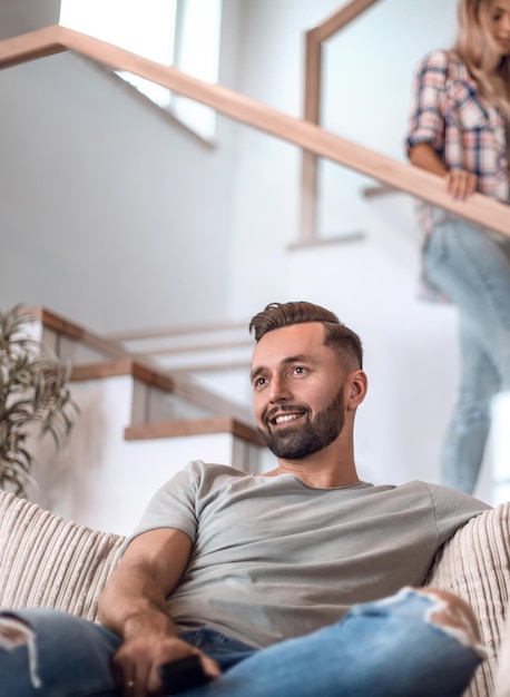 Schließen Sie herauf den jungen Mann, der auf Sofa sitzt