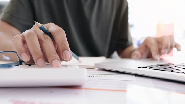 Schließen Sie herauf des Geschäftsmanns oder der Buchhalterhand, die Stift hält, der auf Rechner arbeitet, um Geschäftsdaten, Buchhaltungsdokument und Laptop-Computer im Büro, Geschäftskonzept zu berechnen