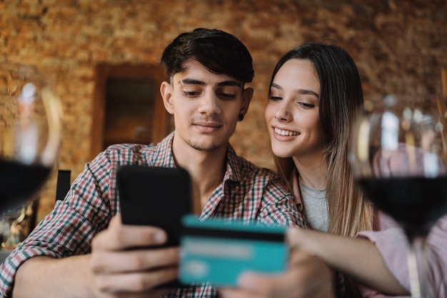Schließen Sie herauf des glücklichen jungen kaukasischen Paares, das online auf Smartphone mit Kreditkarte einkauft.