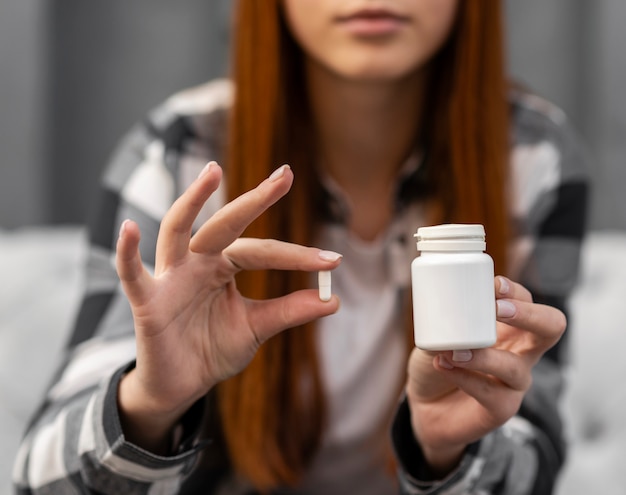 Foto schließen sie herauf die frau, die weiße kapsel hält