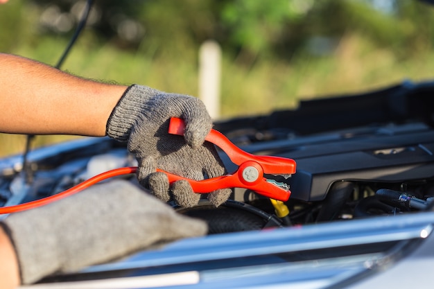 Schließen Sie herauf die Hand des Autotechnikers, der Kabel hält, um an Batterie anzuschließen