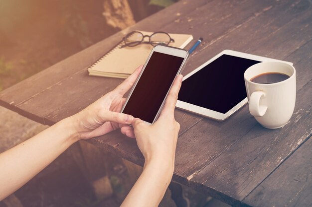 Schließen Sie herauf die Handfrau, die Telefon in der Kaffeestube, Weinlesefilter hält.