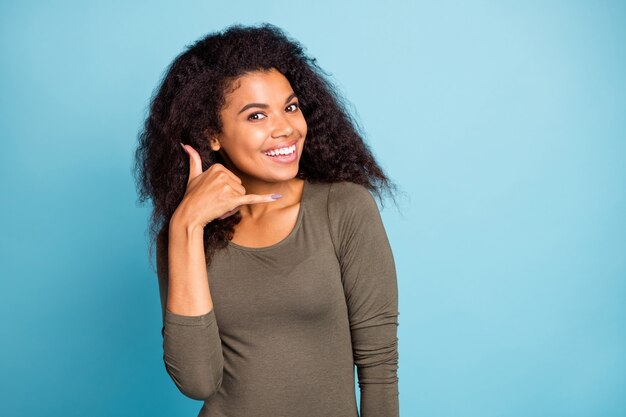 Schließen Sie herauf Foto des positiven fröhlichen afroamerikanischen Mädchens verträumten Traum stellen Sie sich vor, dass sie Kommunikation mit ihrem Freund hat, rufen Sie mich durch Handy tragen lässigen Stil Pullover isoliert blaue Farbe Wand