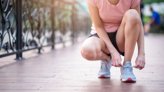 Schließen Sie herauf Frau binden Schuhe im Park