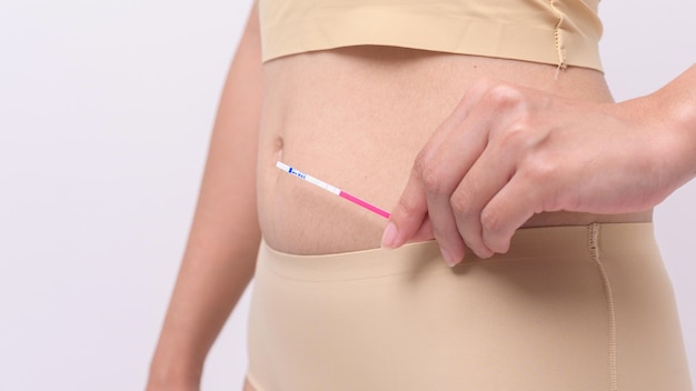 Schließen Sie herauf Frau, die Ovalation LH-Test oder HCG-Schwangerschaftstest auf weißem Hintergrund verwendet