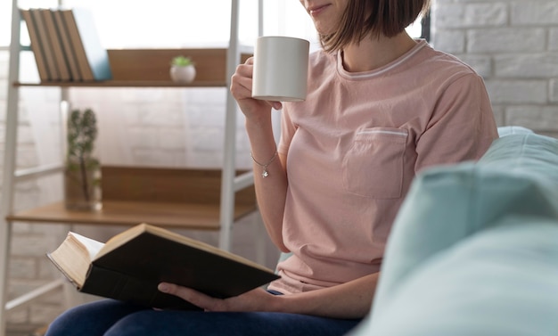 Schließen Sie herauf Frau mit Tasse und Buch