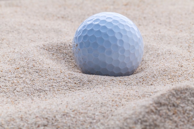 Schließen Sie herauf Golfball in der flachen Schärfentiefe des Sandbunkers.