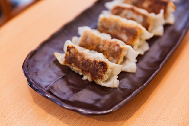 Schließen Sie herauf Gyoza (japanische gebratene Teigtaschen) mit Soße und Sesamöl.