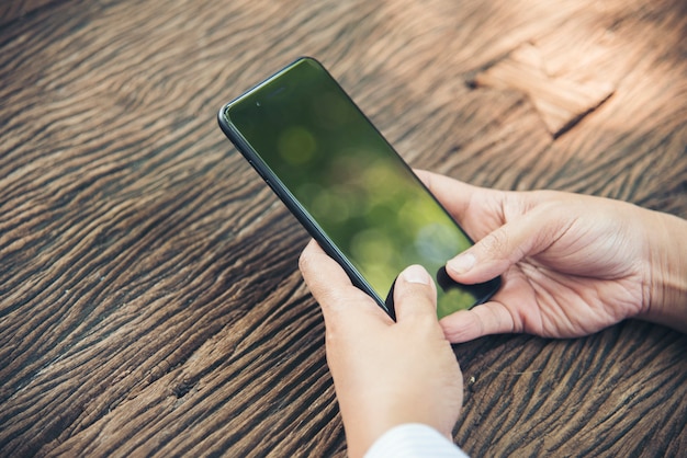 Schließen Sie herauf Hände der schönen Frau, die Smartphone im Freien im Park verwendet.