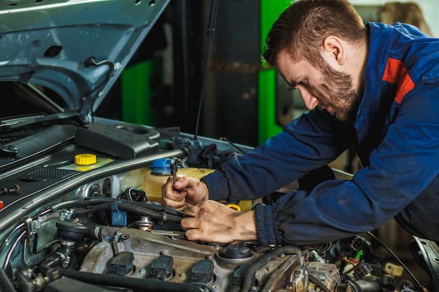 Schließen Sie herauf Hände des unerkennbaren Mechanikers, der Autoservice und -wartung tut