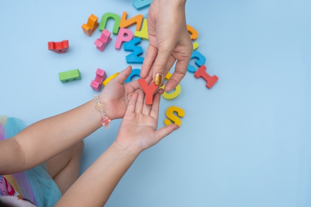 Schließen Sie herauf Hände von Mutter und Tochter, die das Alphabet studieren