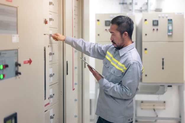 Schließen Sie herauf Hand des Ingenieurs oder Elektriker, der arbeitet, überprüfen Sie das elektrische System mit Tablette im Werk.