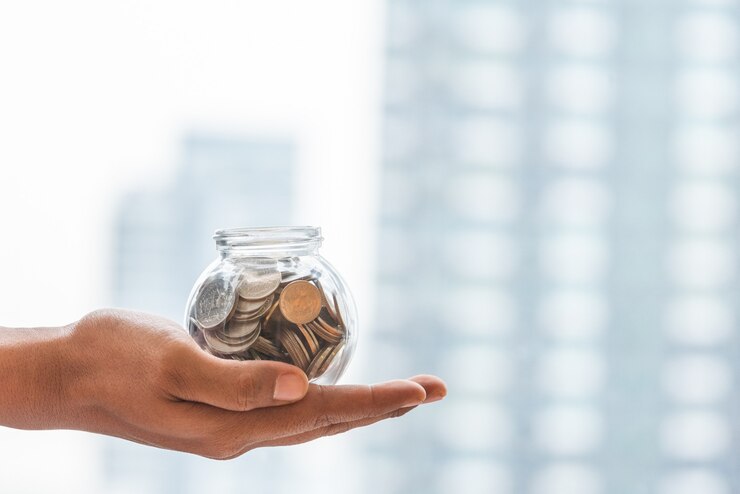 Schließen Sie herauf Hand, die Geld im Glas mit Kopienraum hält