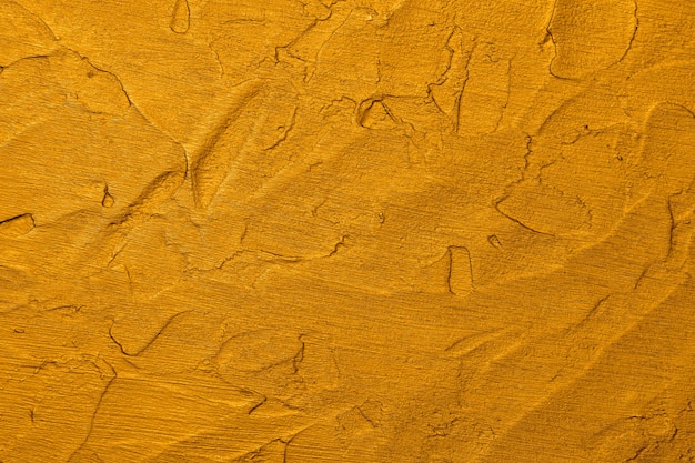 Schließen Sie herauf lebendige goldgelbe abstrakte Hintergrundbeschaffenheit der unebenen Schmutzfläche mit Pinselstrichen von Gips und Farbe