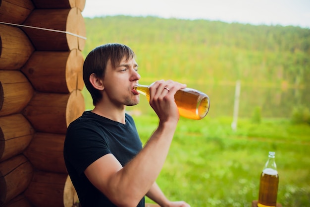 Schließen Sie herauf Mann, der Bier vom Glas an der offenen Luft nahe dem Pool trinkt. Alkohol- und Freizeitkonzept.