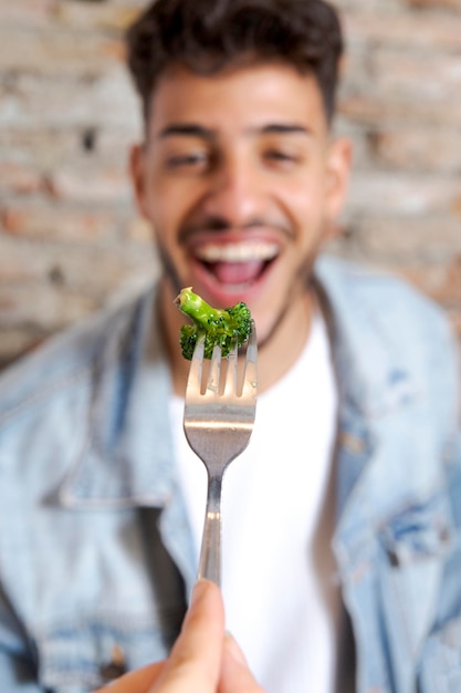 Foto schließen sie herauf mann, der brokkoli isst