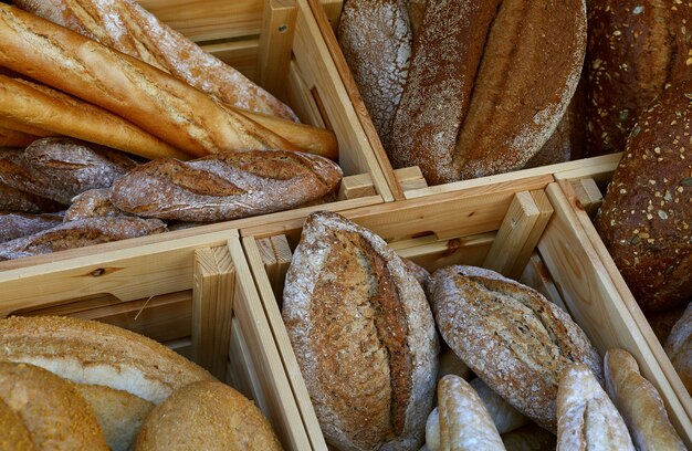 Schließen Sie herauf mehrere sortierte frische Weizenbrotbrote und Baguettes in der Holzkiste auf Einzelhandelsanzeige des Bäckereigeschäfts, hohe Winkelansicht