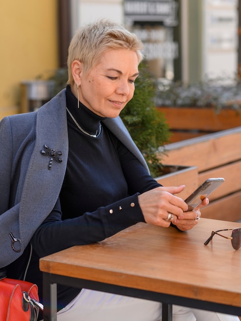 Schließen Sie herauf Porträt der Geschäftsfrau mittleren Alters unter Verwendung des Telefons im Freien