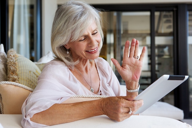 Schließen Sie herauf Porträt der glücklichen älteren Frau zu Hause mit Touch Screen Tablette