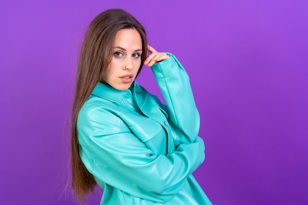 Schließen Sie herauf Porträt der jungen kaukasischen Frau im blauen Trenchcoat, der auf purpurrotem Studiohintergrund lokalisiert wird