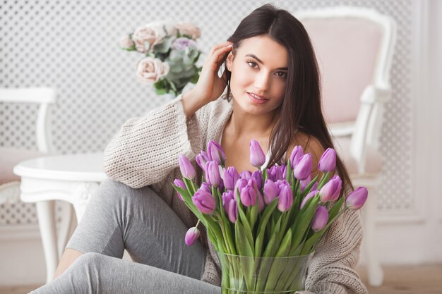 Schließen Sie herauf Porträt der schönen jungen Frau, die Blumen hält. Attraktive Frau mit Tulpen